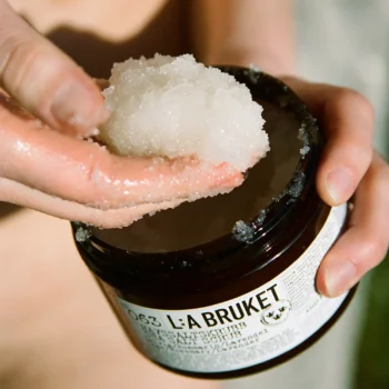 Soldränkta fingrar tar en mängd saltscrub ur produktens glasburk.